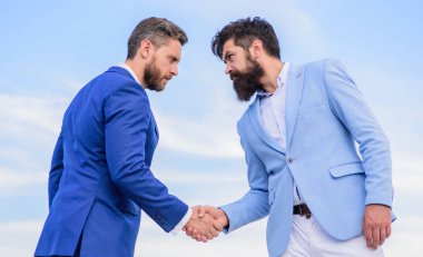 Girişimcilerin tokalaşması başarılı bir anlaşmayı simgeliyor. İş ortağına güvenmen gerektiğine dair bir işaret. Erkekler el sıkışırken mavi gökyüzü arkaplanı. İş anlaşması her iki taraf tarafından da kabul edildi