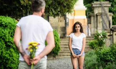 İlk izlenim her zaman önemlidir. Adam çiçek buketi arka beklediği romantik tarih arkasında gizler. Onun için sürpriz. Çift Toplantı tarihi park arka plan için. Aşk hayatını değiştirecek ipuçları dating