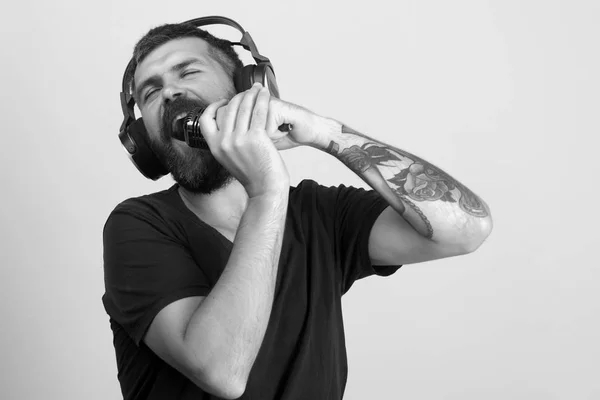 O DJ com barba usa auscultadores. Homem canta em fundo rosa , — Fotografia de Stock