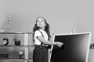 Kız boş yazı tahtası üzerinde kopya alanı yazar. Çocukluk ve çalışma zaman kavramı. Rüya gibi yüz ile kız öğrenci