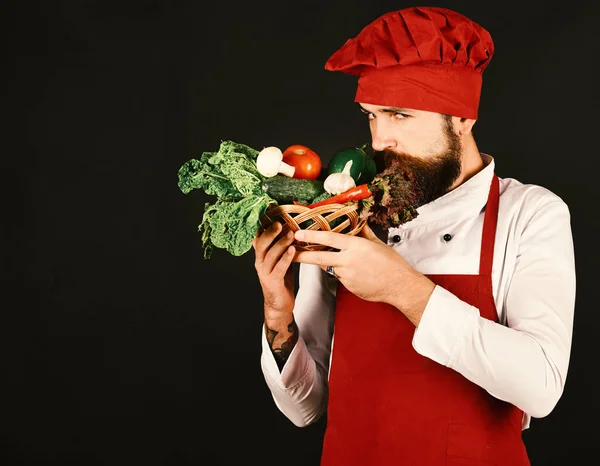 Hombre con barba sobre fondo negro, espacio para copiar. Concepto de dieta vegetariana. Cocinar con la cara difícil en uniforme de color burdeos — Foto de Stock