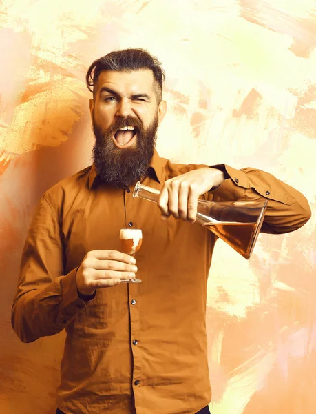 holding glass tube or flask and doing alcoholic red shot on colorful texture background. Brutal hipster holding alcoholic shot and glass tube or flask