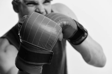 Defocused beyaz arka plan, deri kutu ekipman ile sporcu. Adam kıl ve deli yüz giyer boks eldivenleri, portre