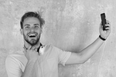 Amerikan yakışıklı adam kulaklıklarla sakallı. Müzikal yaşam tarzı. Mavi gözlü şık hipster ile smartphone.