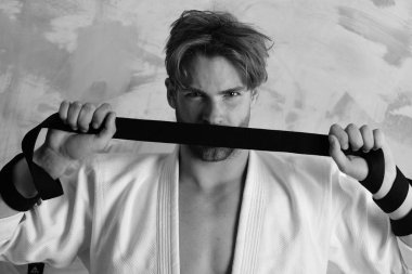 Adam ciddi görme ve renkli arka plan üzerinde kıl. Adam beyaz kimono holding siyah kuşak teşkil etmektedir. Karate avcı