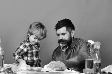 Temizlik eğitimi kavramı. Adam ve çocuk sünger ve köpük ile ahşap masa Temizleme