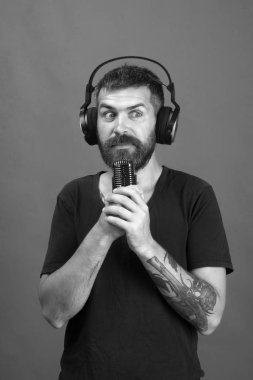 Sakallı DJ kulaklık takıyor. Şarkıcı sakal ve şok yüz ile müzik dinliyor. Adam yeşil arka plan üzerinde mikrofon tutar. Teknolojileri ve müzik konsepti.