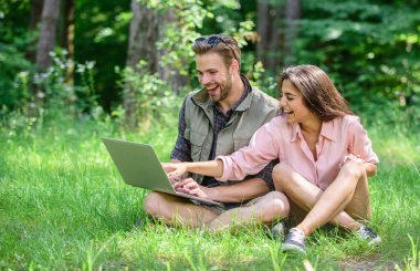 Modern teknolojileri online ve herhangi bir çevre koşulları çalışmalarına olmak için fırsat verir. Adam ve kız dizüstü bilgisayar ekranına bakarak. Serbest fırsat. Çift gençlik eğlence dizüstü bilgisayar ile açık havada harcamak