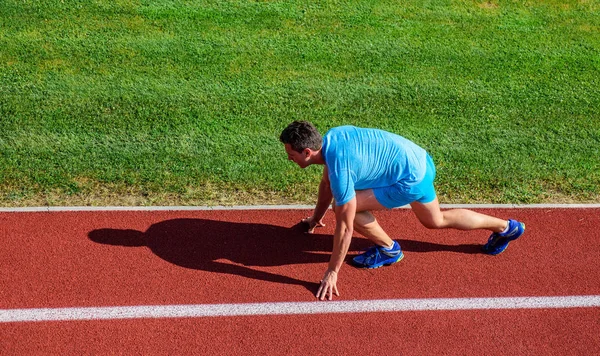 Running tips for beginners. Man athlete stand low start position stadium path. Runner ready to go. Joint mobility exercises to improve flexibility and function. Athlete runner prepare to race