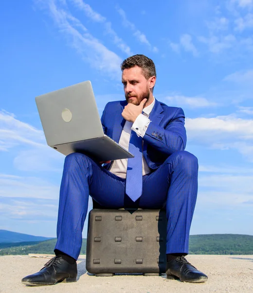 ノート パソコンを持つビジネスマンにはブリーフケースの青い空を背景が座っています。ノート パソコン必須属性現代ビジネスマン。近代的な技術のポータブル デバイス機会作品世界。新鮮な空気のビジネス — ストック写真