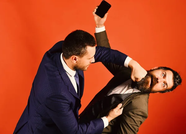 Hombre de negocios con cara asustada sostiene el teléfono móvil. Hombres con barba luchan sobre fondo rojo . —  Fotos de Stock