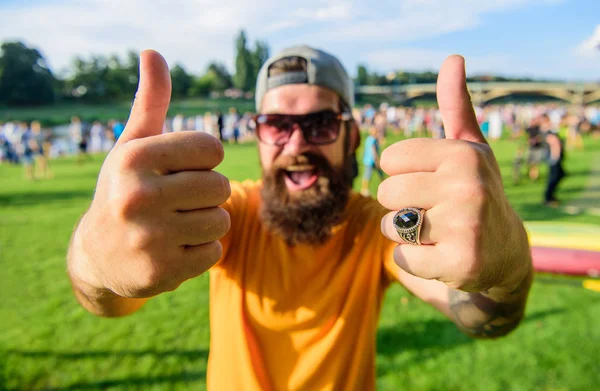 Book ticket now summer festival. Highly recommend top list events. Hipster visiting event picnic fest or festival. Man cheerful face shows thumb up. Man bearded in front of crowd riverside background