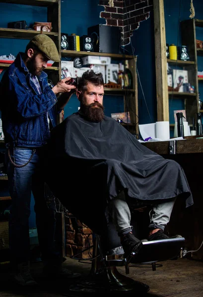 Barbiere con clipper taglio capelli su nuca di cliente. Un cliente hipster che si taglia i capelli. Il barbiere con tagliacapelli lavora su taglio di capelli di sfondo di barbuto di barbiere. Concetto di acconciatura hipster — Foto Stock