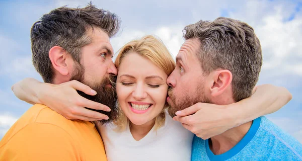 La signora gode di relazioni romantiche entrambi ammiratori. Gli uomini si innamorano della stessa donna. Le piacciono le attenzioni maschili. Triangolo dell'amore. Una ragazza si abbraccia con due ragazzi. Questioni di relazioni romantiche. Gli uomini baciano le stesse guance ragazza — Foto Stock