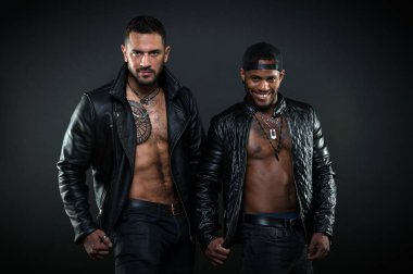 Çıplak torsolar ile vücut geliştiriciler. Geniş gülümseme şapkası olan Afrika neşeli adam. Acımasız beyaz adam kıllı göğüs dövme ile. Motorcu deri mont kaslı vücut, erkeklik kavramı üzerinde