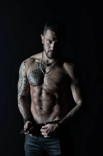 Hombre barbudo sin camisa con el torso en forma. Hombre con diseño de tatuaje en la piel. Modelo de moda hebilla cinturón de cuero en jeans. Deportista con seis paquetes y ab. Fitness con deporte y bodycare, filtro vintage — Foto de Stock