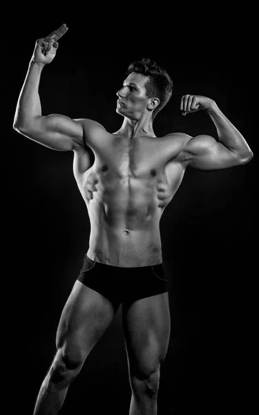 Sportler. muskulöser Sportler mit Sixpack, schwarz-weiß. Sportler Bodybuilder Punkt auf seinen Muskel. Bizeps und Trizeps des Sportlers. Täglich voller Sport. — Stockfoto
