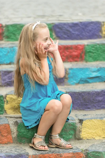 Małe dziecko szczęśliwy dziewczyna w niebieskiej sukience na schody kolorowe — Zdjęcie stockowe