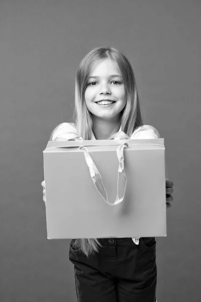 A la chica le gusta comprar ropa de moda en el centro comercial. Chica en la cara sonriente lleva bolsa de compras, aislado sobre fondo blanco. Niña con el pelo largo aficionado a las compras. Concepto de compras —  Fotos de Stock