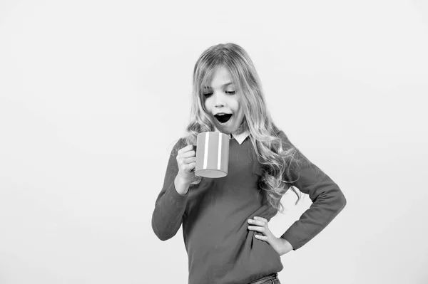 Здоров'я та здоровий напій. Дитяча посмішка з блакитною чашкою на помаранчевому фоні. Дівчина з довгим світлим волоссям у червоному светрі тримає кухоль. Чай або перерва на каву. Здоров'я та здоровий напій, копіювання простору — стокове фото