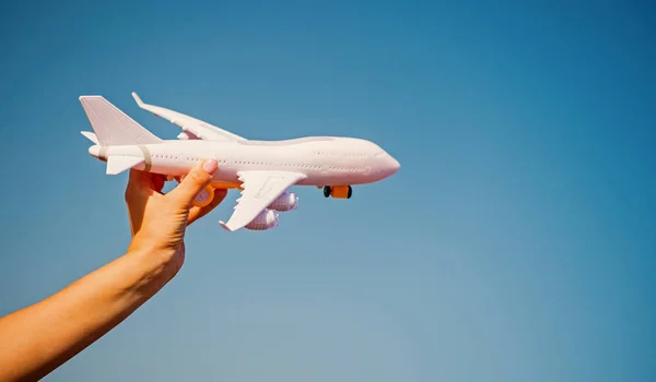 Белый игрушечный самолет в женской руке на солнечном голубом небе — стоковое фото