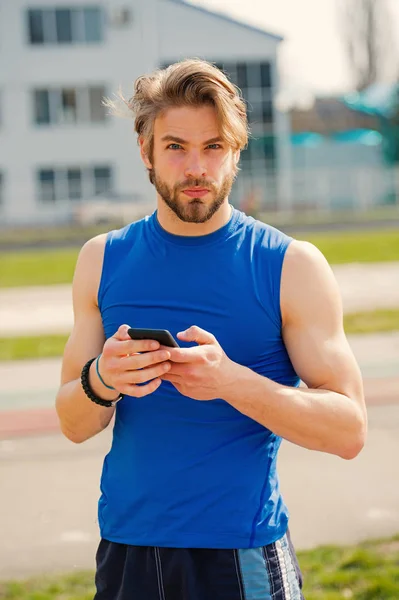 athletic bearded man with muscular body holds cell phone