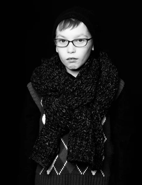 Petit garçon ou mignon nerd kid dans des lunettes, chapeau et foulard tricoté à la mode sur fond noir. — Photo