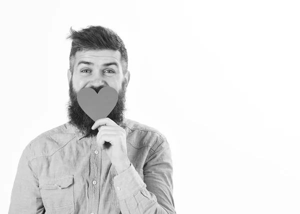 Homem com barba e cara feliz celebra dia dos namorados, espaço de cópia. Hipster em camisa jeans detém coração vermelho — Fotografia de Stock