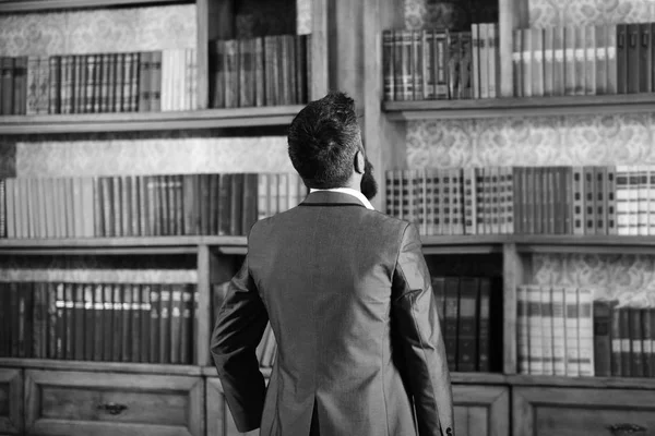 Library books concept. Man in formal wear looks at library books
