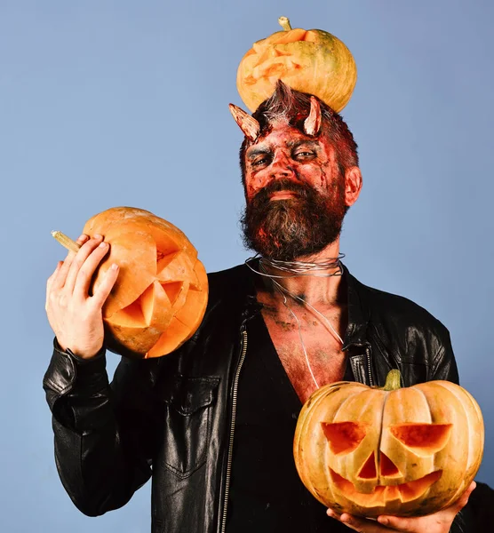 Monstre avec des décorations d'octobre. Homme portant un maquillage effrayant tient citrouilles sur fond bleu . — Photo