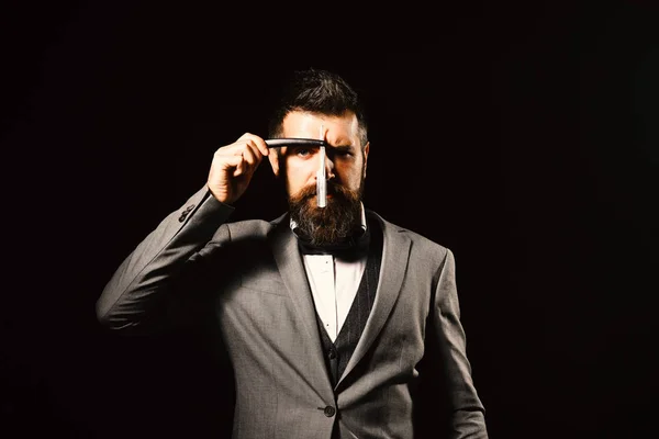 Man with long beard holds blade for razor in front of face. Barbershop advertising concept. Businessman with strict face