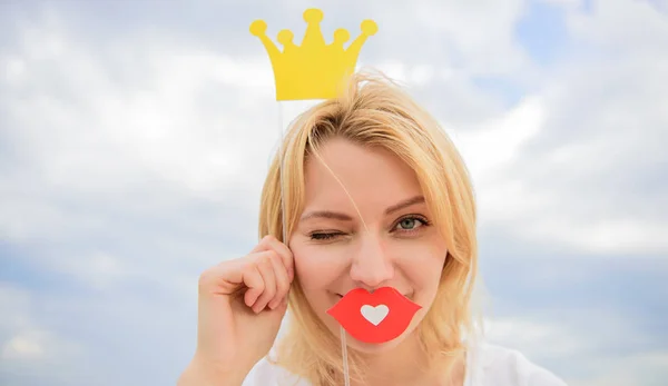 爱玩的公主金发女子手持硬纸板头冠或王冠，红唇代表爱情的天空背景。公主夫人高高兴兴地戴着黄色的王冠.梦想每个女孩都能成为皇后 — 图库照片