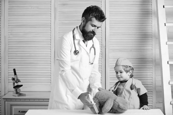 Veteriner ve küçük yardımcısı enjeksiyon oyuncak ayı için yapmak. Baba ve çocuk meşgul yüzü olan doktor oynamak. — Stok fotoğraf