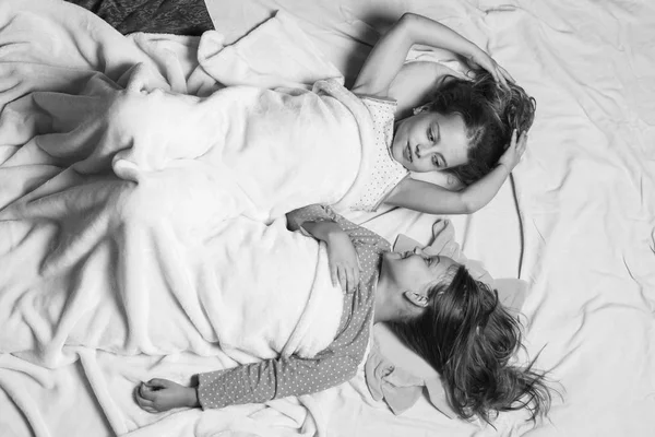 Childhood and good morning concept. Schoolgirls have rest looking at each other. Kids in pajamas — Stock Photo, Image