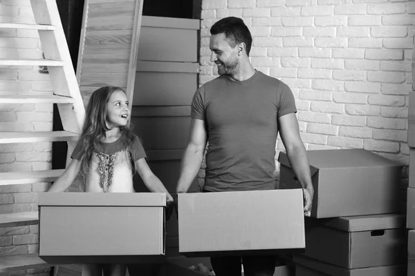Girl and man with smiling faces in room on white brick wall background. Daughter and father hold boxes and unpack or pack.