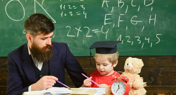 数学のレッスン コンセプトです。正式な摩耗と鏝板の教室で、背景に黒板に生徒の教師。先生と勉強熱心な子供。父は息子の数学を教えてください。 — ストック写真