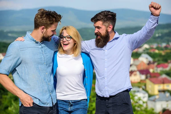 Company reached top. Business team concept. Men with beard in formal shirts and blonde in eyeglasses as successful team. Company of three happy colleagues or partners hugs outdoor, nature background