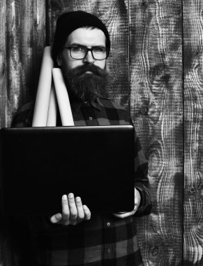 Kaba sakallı, beyaz tenli hippi elinde dizüstü bilgisayar ve el işi kâğıdı tutuyor.