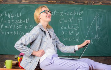 Kadın öğretmen dizüstü sit tablo sınıf kara tahta arka plan tutun. Modern nesil öğretmeni. Resmi olmayan bir ortamda ders. İnanılmaz öğretim görevlisi bayanı tanıyor nasıl dokunmatik modern nesil kal.