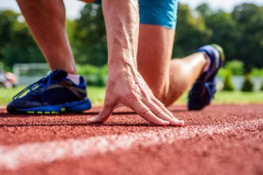 Koşucu yakın gitmeye hazır. Hazır sabit git kavramı. Harika bir spor kariyeri başında. Başlangıç noktası. El değmek iz yolu kapatın. Sporcu koşu parkuru düşük üzerinde el başlangıç pozisyonu