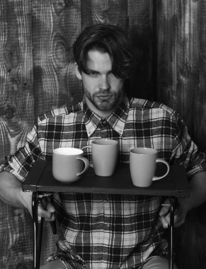 Ahşap arka planda bardakları tutan yakışıklı adam.