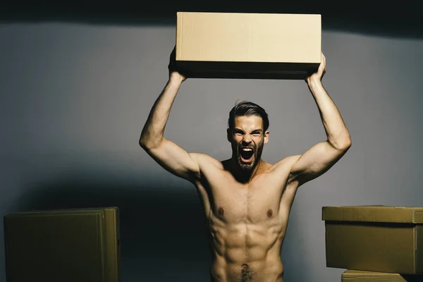 Chico con sexy desnudo torso sostiene caja por encima de la cabeza. — Foto de Stock