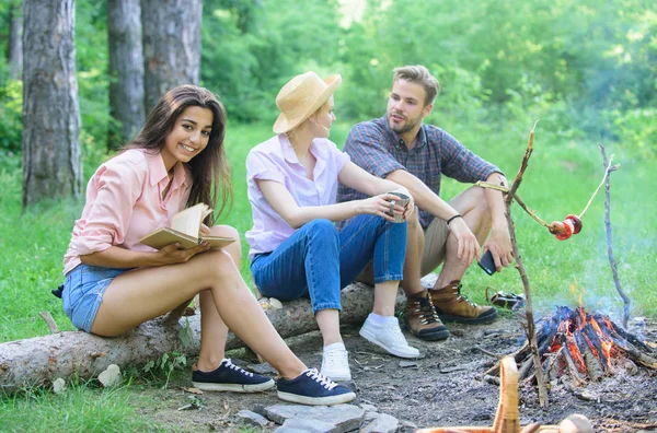 Company friends spend great time picnic or barbecue near bonfire. Idyllic weekend. Friends enjoy weekend barbecue in forest. Group friends spend leisure weekend hike picnic forest nature background