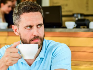 Güne büyük fincan kahve ile başlayın. Adam ciddi bir yüz ihtiyaçlarını enerji şarj sakallı. Geleneksel kahve molası kafe arka plan. Kafein daha enerjik yapar. Ciddi adam zevk kafein içecek kadar yakın