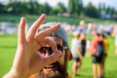 Kalabalık nehir arka plan önünde sakallı adam. Bilet Yaz Festivali önceden rezervasyon yaptırın. Hippi Fest Festivali ziyaret etti. Adam neşeli yüz ok jest görünüyor. Yaz tatil emin olun