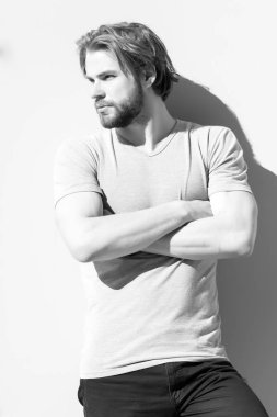 Katlanmış kas elleri ile rahat tshirt adam. Gri duvar sakallı tıraşsız yüzü olan adam. Maço sarışın kıllı güneşli açık. Moda ve stil kavramı