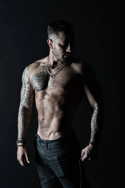 Sportsman or athlete in fashion jeans. Man with tattooed arm and chest. Bearded man with strong torso. Tattoo model with sexy belly. Bodycare with fitness and sport, vintage filter — Stock Photo, Image