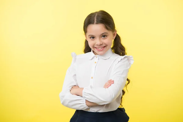 Mignon et confiant. Fille uniforme scolaire souriant visage joyeux fond jaune. Enfant prêt à retourner à l'école fin continuer l'éducation. La tenue formelle de l'écolière est mignonne. Fille heureux retour à l'école — Photo