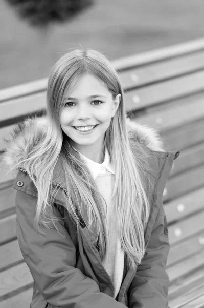 Freizeit, Entspannung, Lebensstil. Mädchen in rotem Mantel sitzen auf Bank im Park. Glückliche Kindheit. Kind mit blonden langen Haaren lächelt draußen. Kinder genießen den Herbsttag — Stockfoto