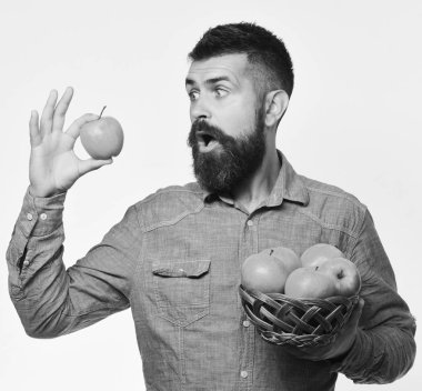 Şaşırmış suratlı çiftçi kırmızı elma tutuyor. Sakallı adam